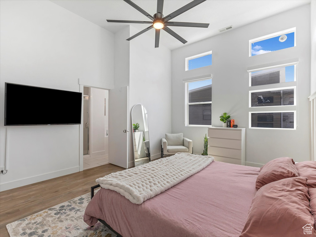 Bedroom with a towering ceiling, wood finished floors, and ceiling fan