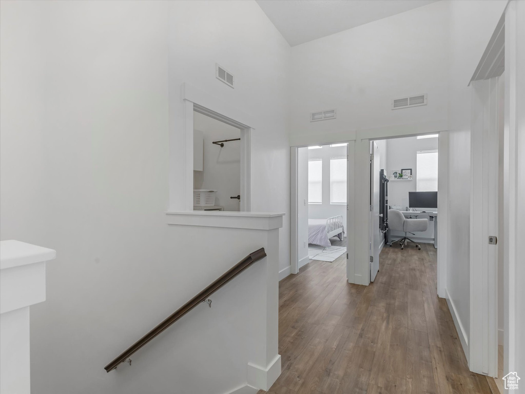 Corridor featuring an office area, an upstairs landing, wood finished floors, and a high ceiling
