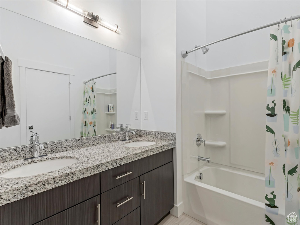Full bath featuring shower / bath combo with shower curtain and double vanity