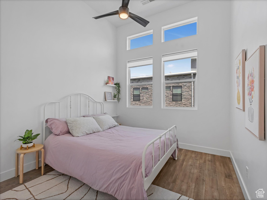 Bedroom with wood finished floors, ceiling fan, and a high ceiling