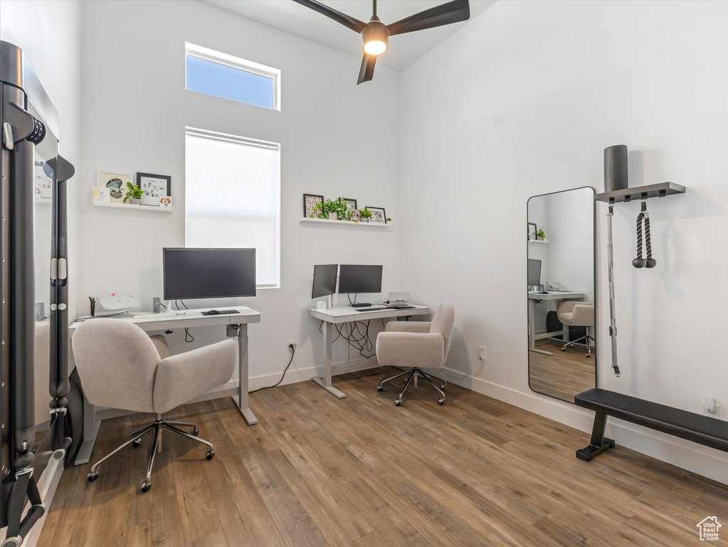 Home office with a towering ceiling, wood finished floors, and ceiling fan