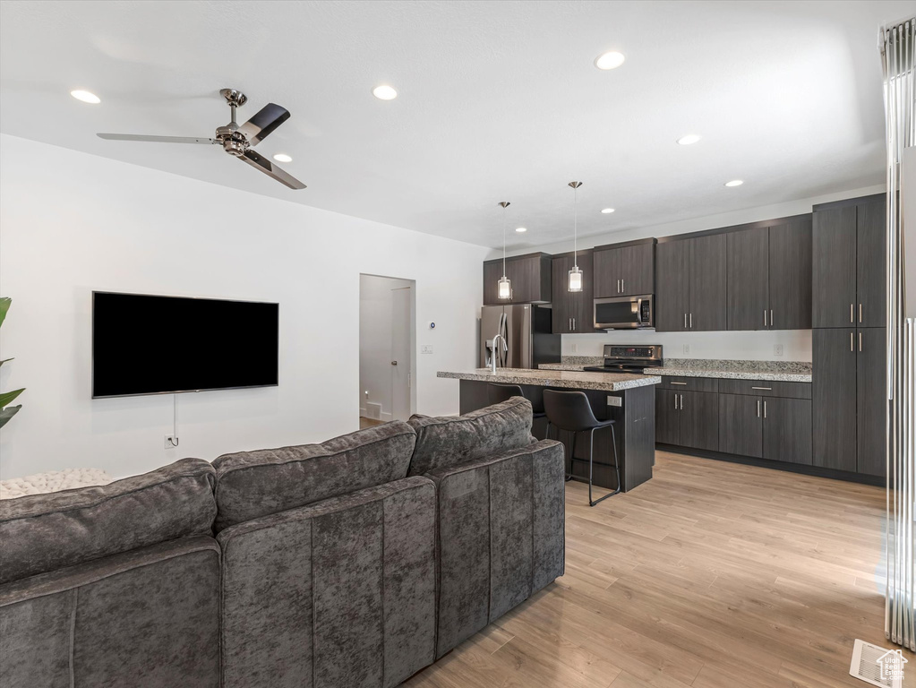 Living room with light wood-style flooring, recessed lighting, and ceiling fan