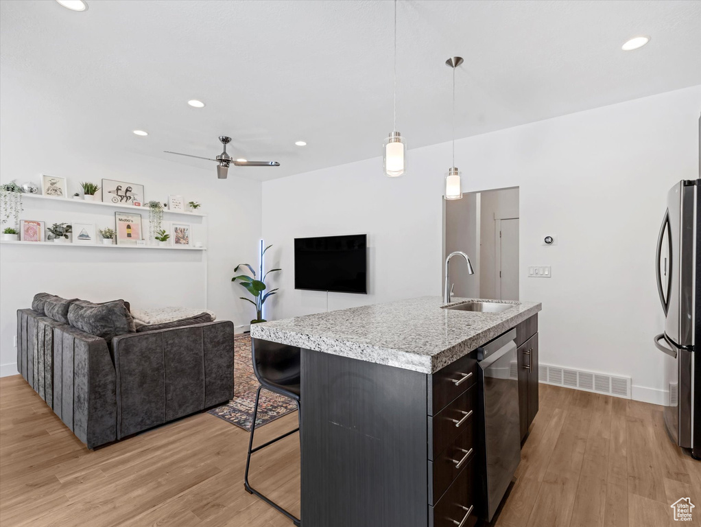 Kitchen featuring freestanding refrigerator, open floor plan, a ceiling fan, light wood finished floors, and recessed lighting