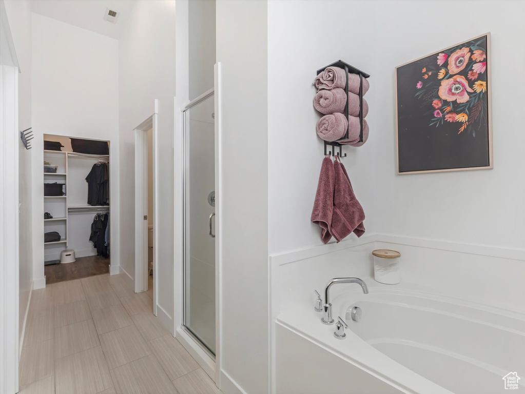 Bathroom featuring a shower stall, a bath, and a walk in closet