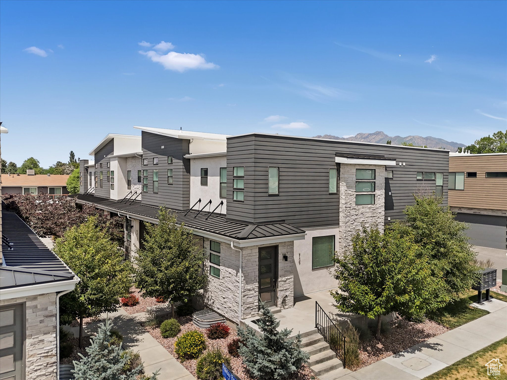 Modern home featuring stone siding, a standing seam roof, a mountain view, a metal roof, and a residential view