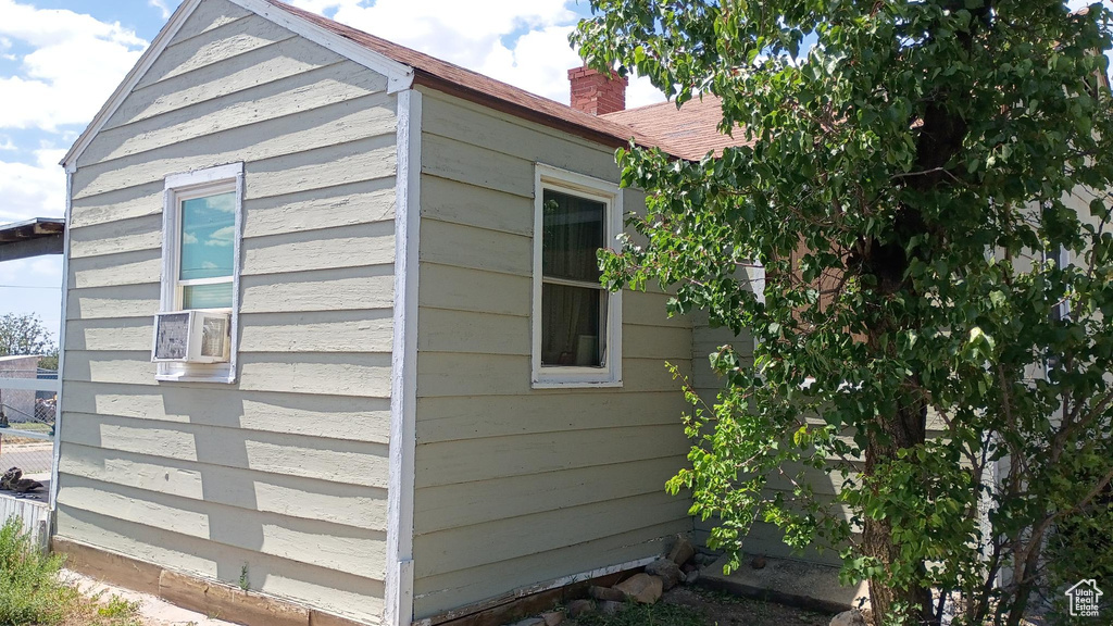 View of side of property featuring a chimney and cooling unit