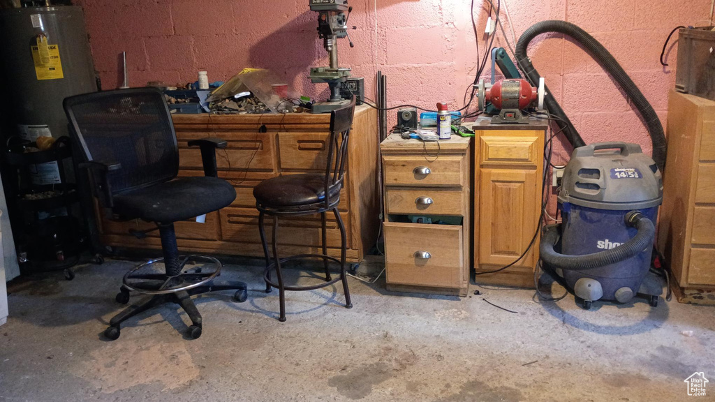 Misc room featuring unfinished concrete floors, water heater, and concrete block wall