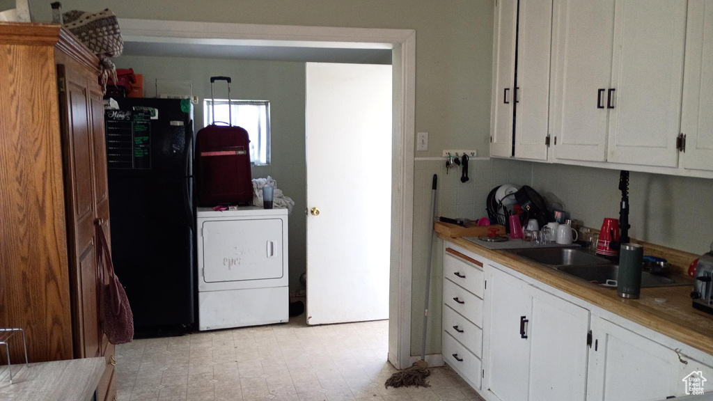 Kitchen featuring white cabinetry, washer / dryer, freestanding refrigerator, and light countertops
