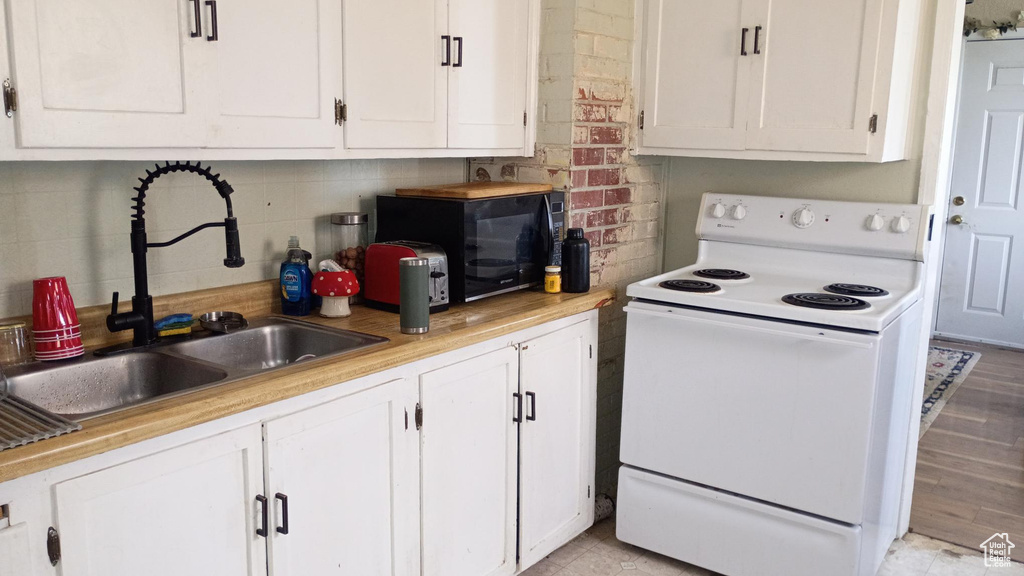 Kitchen with white electric stove, black microwave, and white cabinets