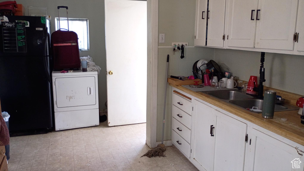 Kitchen with freestanding refrigerator, white cabinets, and light countertops
