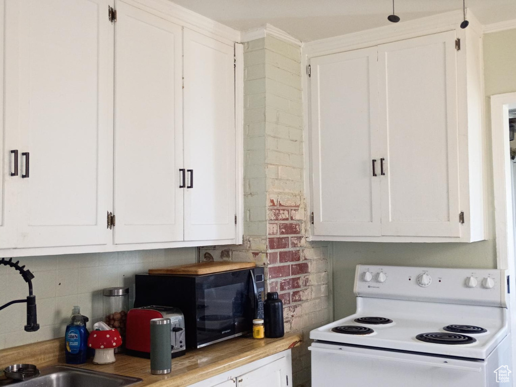 Kitchen featuring electric range, white cabinets, black microwave, light countertops, and decorative backsplash