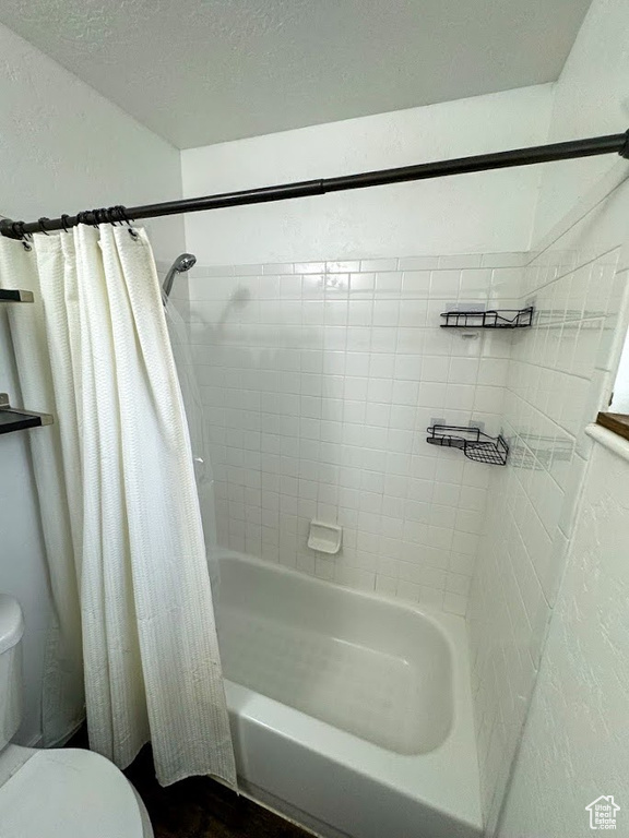 Bathroom with shower / bath combination with curtain and wood finished floors