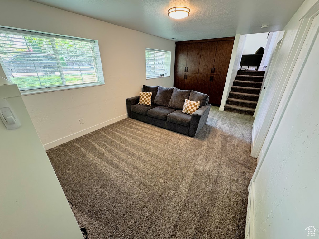 Carpeted living area featuring stairs and baseboards