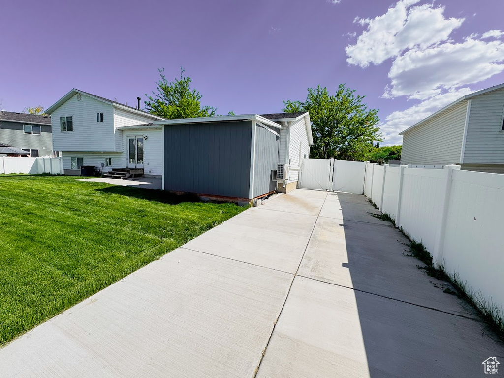 View of side of property featuring entry steps, a fenced backyard, driveway, a patio area, and a gate