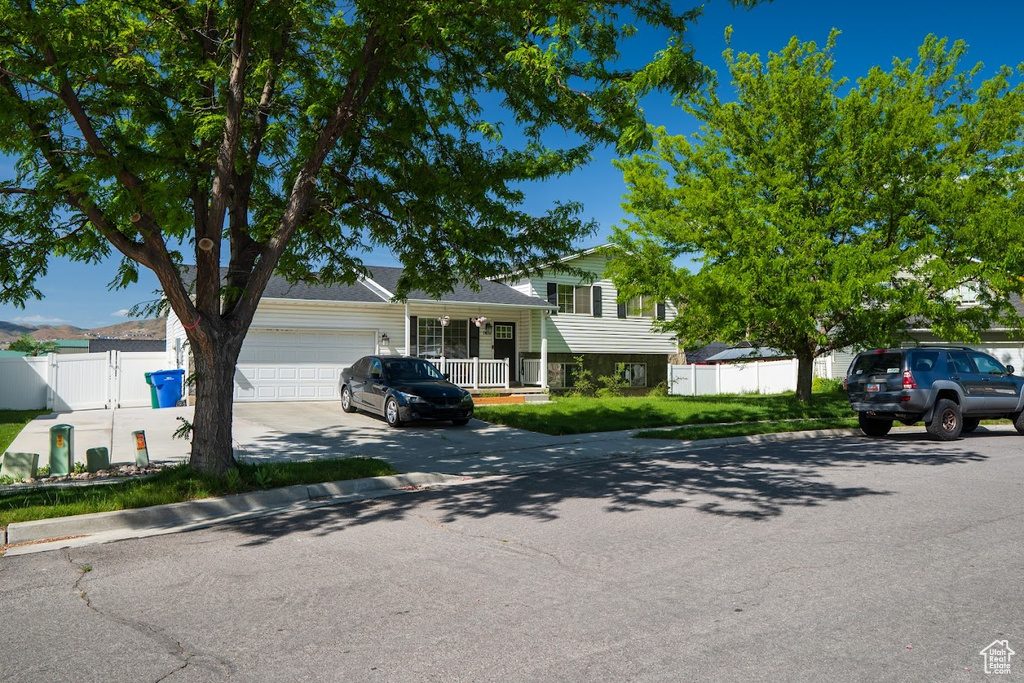 Tri-level home with driveway, an attached garage, and a porch