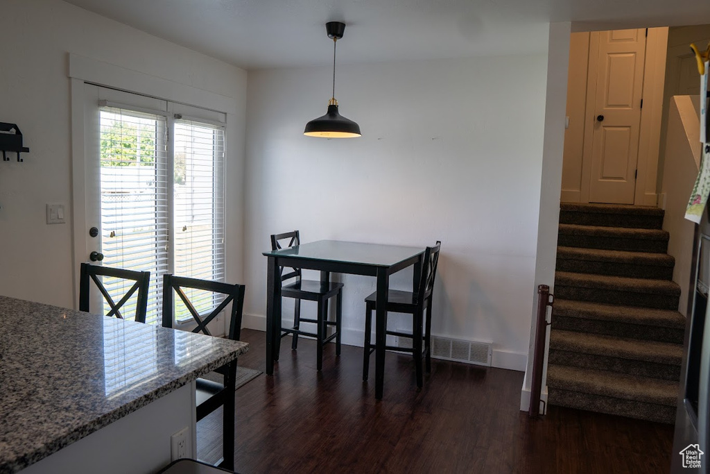 Dining space with dark wood-type flooring and stairway
