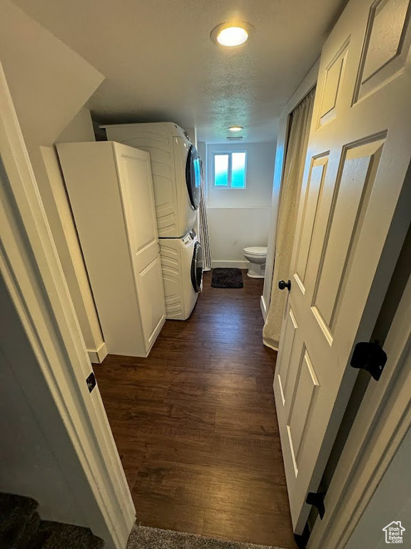 Laundry room with stacked washer / dryer and dark wood-style floors