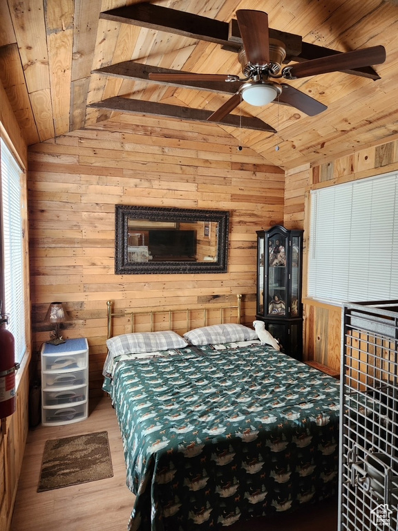 Bedroom with wood ceiling, vaulted ceiling, wooden walls, wood finished floors, and ceiling fan