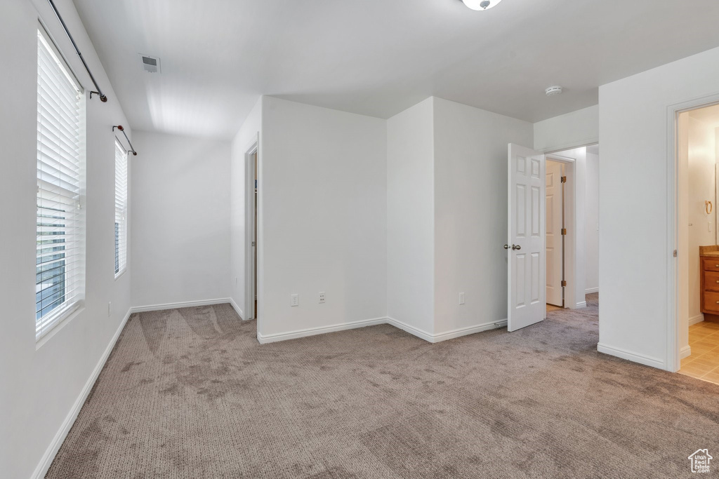 Unfurnished bedroom with carpet, multiple windows, and ensuite bath