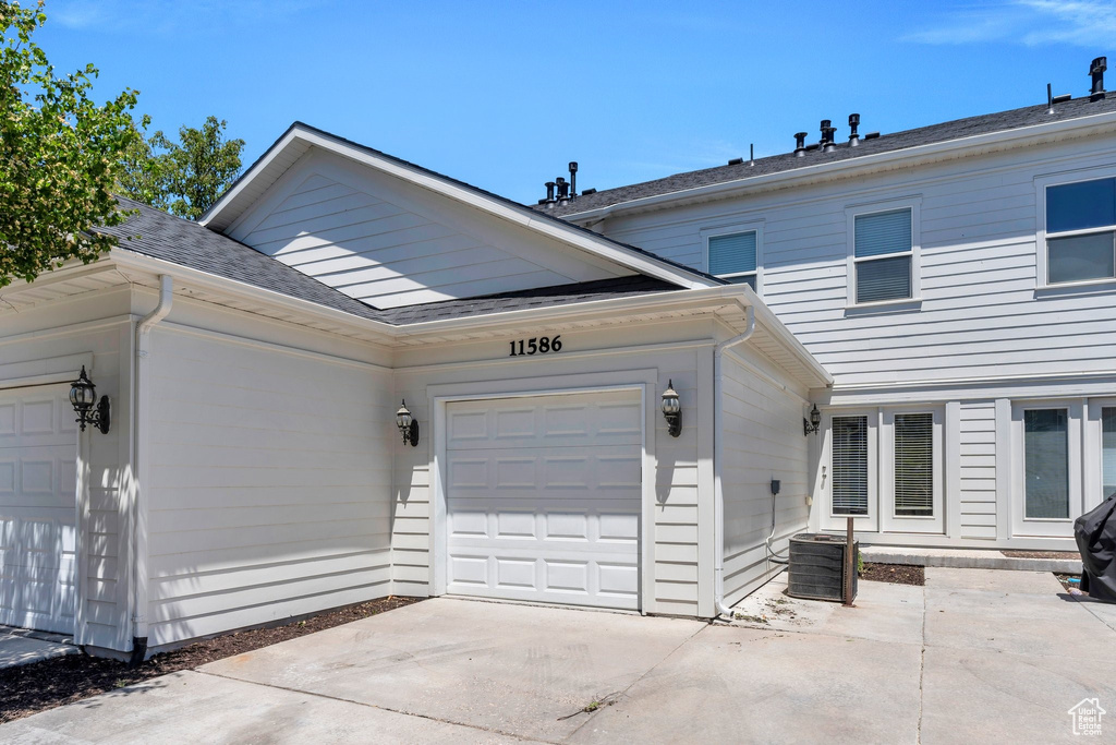 View of front of property with an attached garage, driveway, and roof with shingles