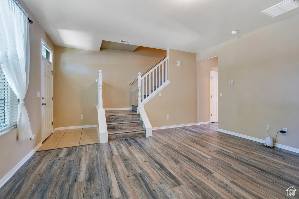 Unfurnished living room featuring wood finished floors and stairway