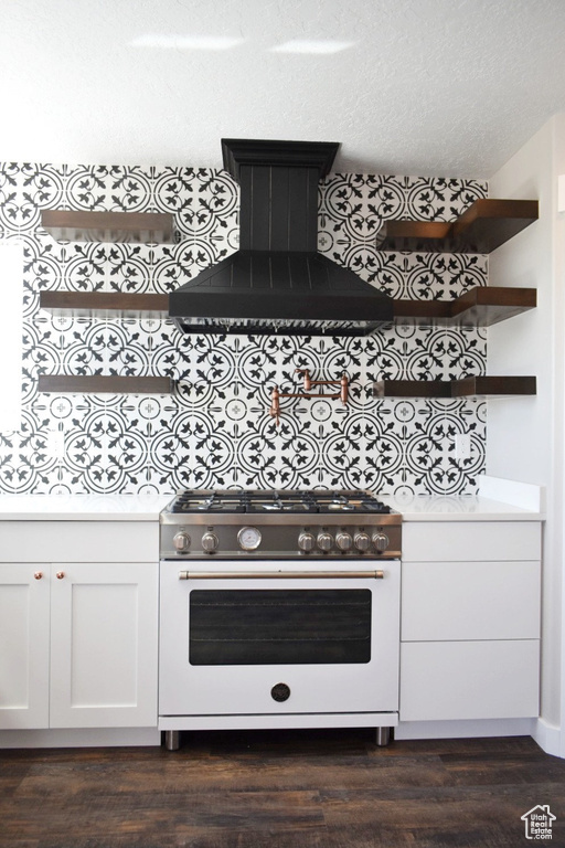 Kitchen featuring high end range, wall chimney range hood, white cabinetry, and dark wood-type flooring