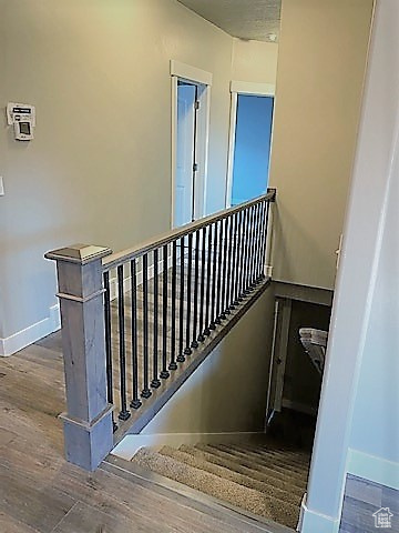Staircase with wood finished floors and baseboards