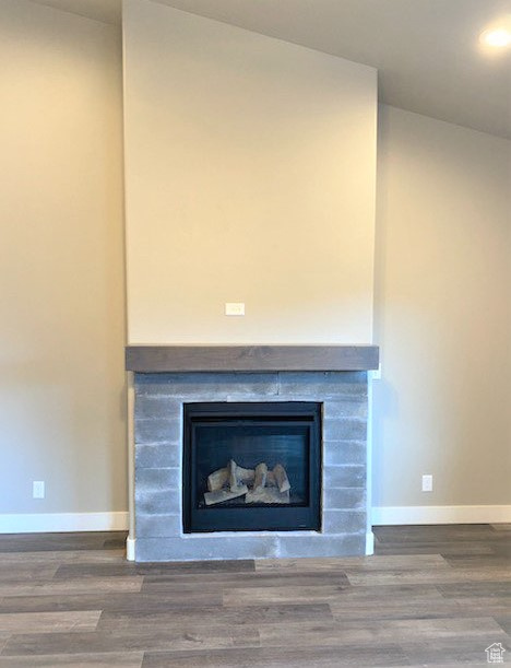 Detailed view of a fireplace, wood finished floors, and recessed lighting