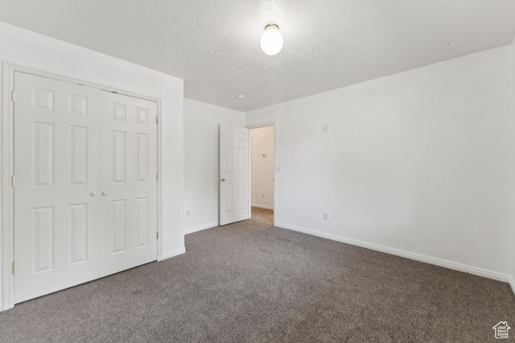 Unfurnished bedroom featuring carpet, a textured ceiling, and a closet