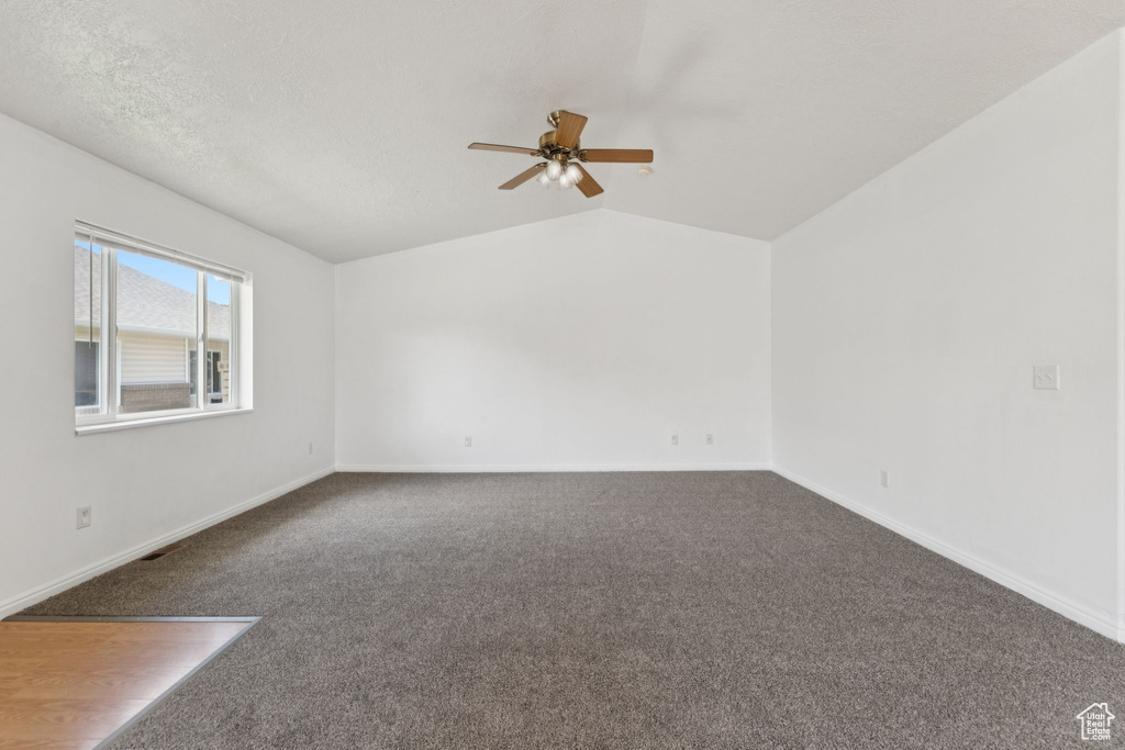Carpeted empty room with ceiling fan and lofted ceiling