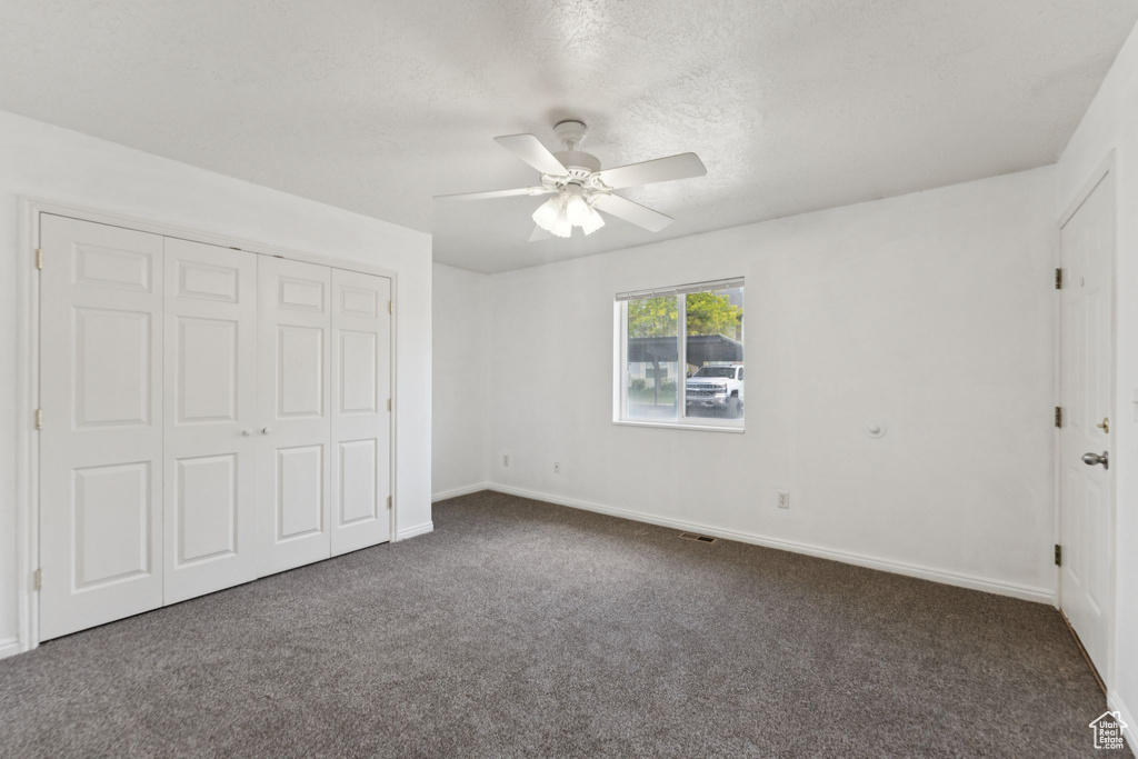 Unfurnished bedroom featuring carpet floors, a closet, a ceiling fan, and a textured ceiling