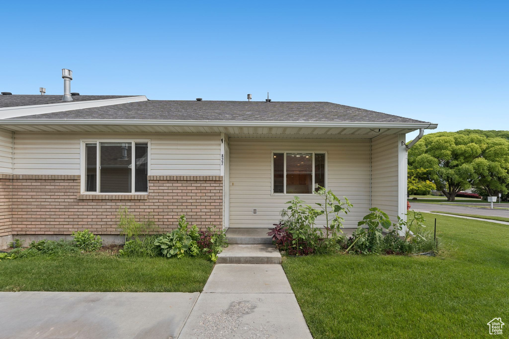 Bungalow-style house with a front lawn, a shingled roof, and brick siding