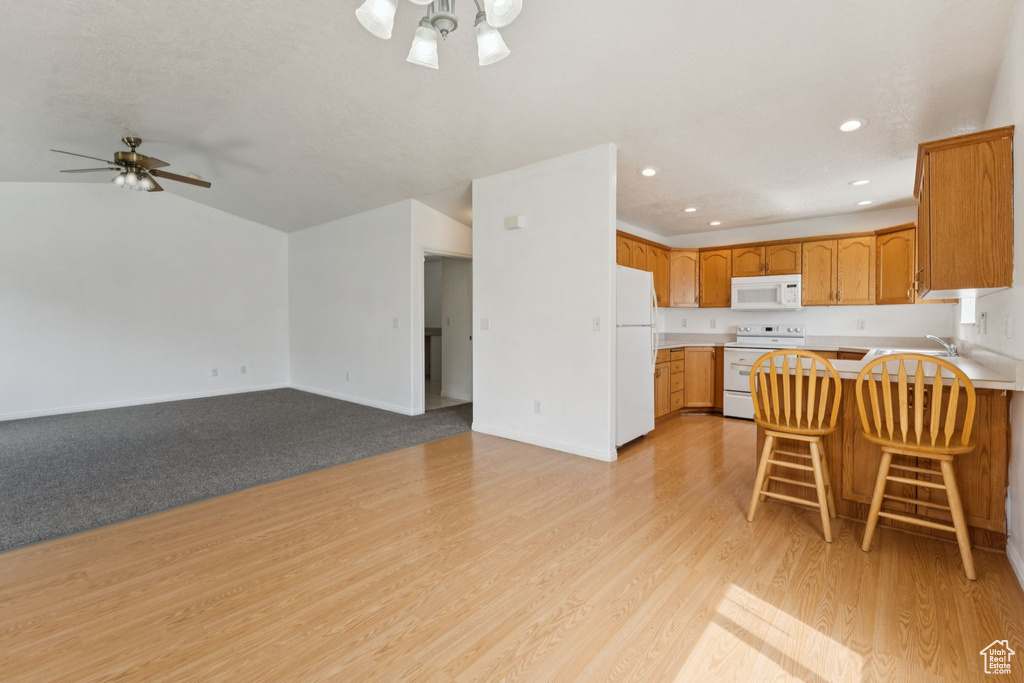 Kitchen with white appliances, ceiling fan, a peninsula, open floor plan, and recessed lighting