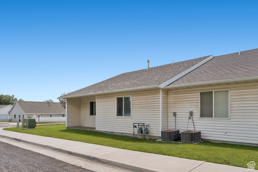 View of home\'s exterior with a shingled roof and a lawn