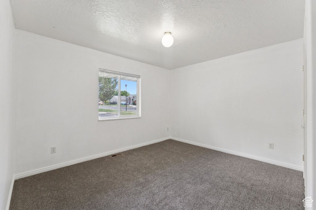 Carpeted empty room featuring a textured ceiling and baseboards