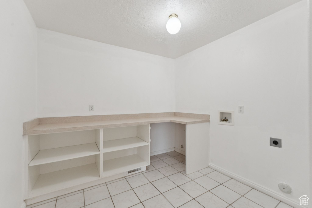 Laundry room featuring electric dryer hookup, washer hookup, a textured ceiling, and light tile patterned floors