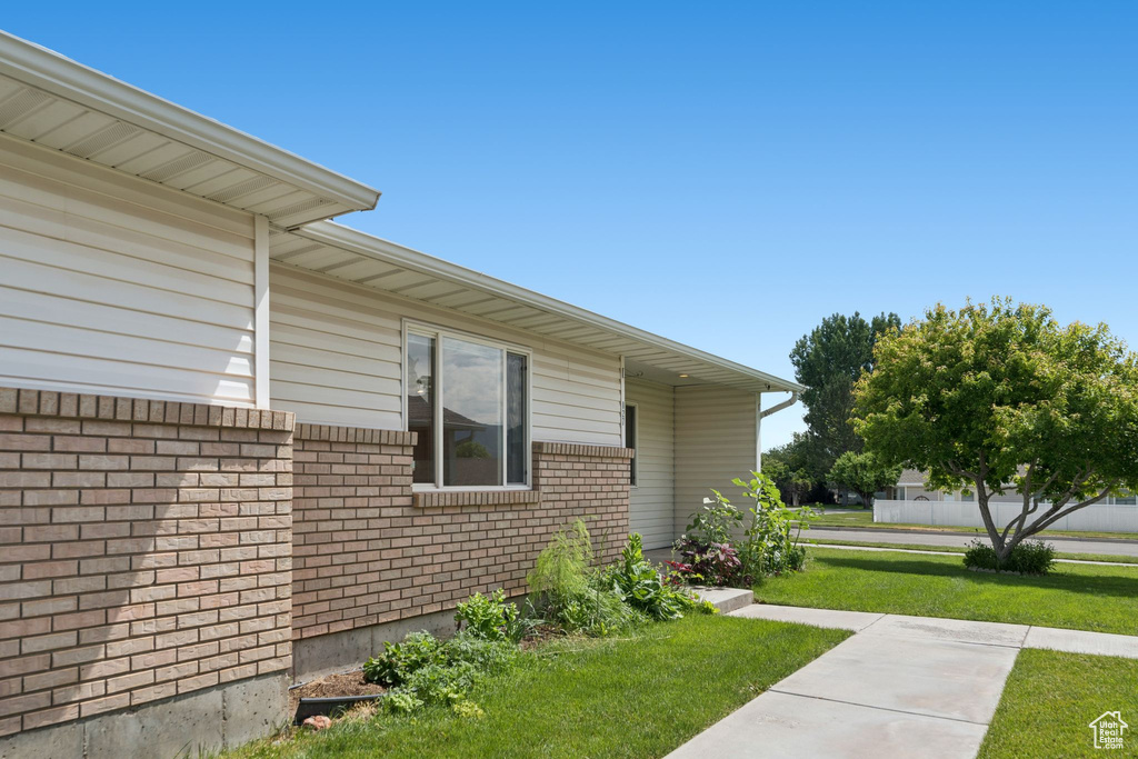 View of property exterior featuring a lawn and brick siding