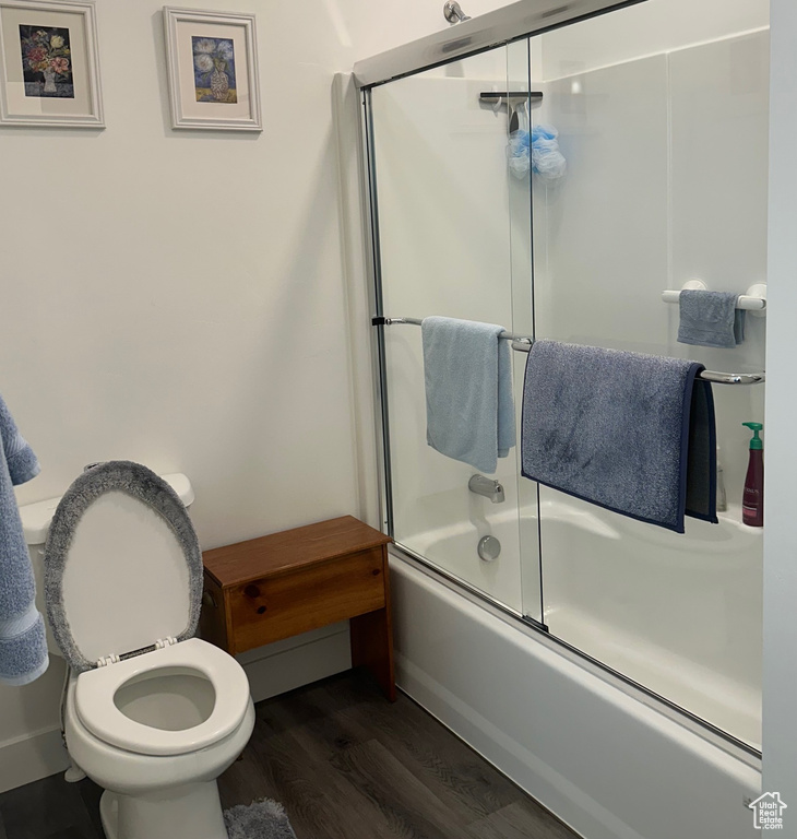 Bathroom with wood finished floors and combined bath / shower with glass door