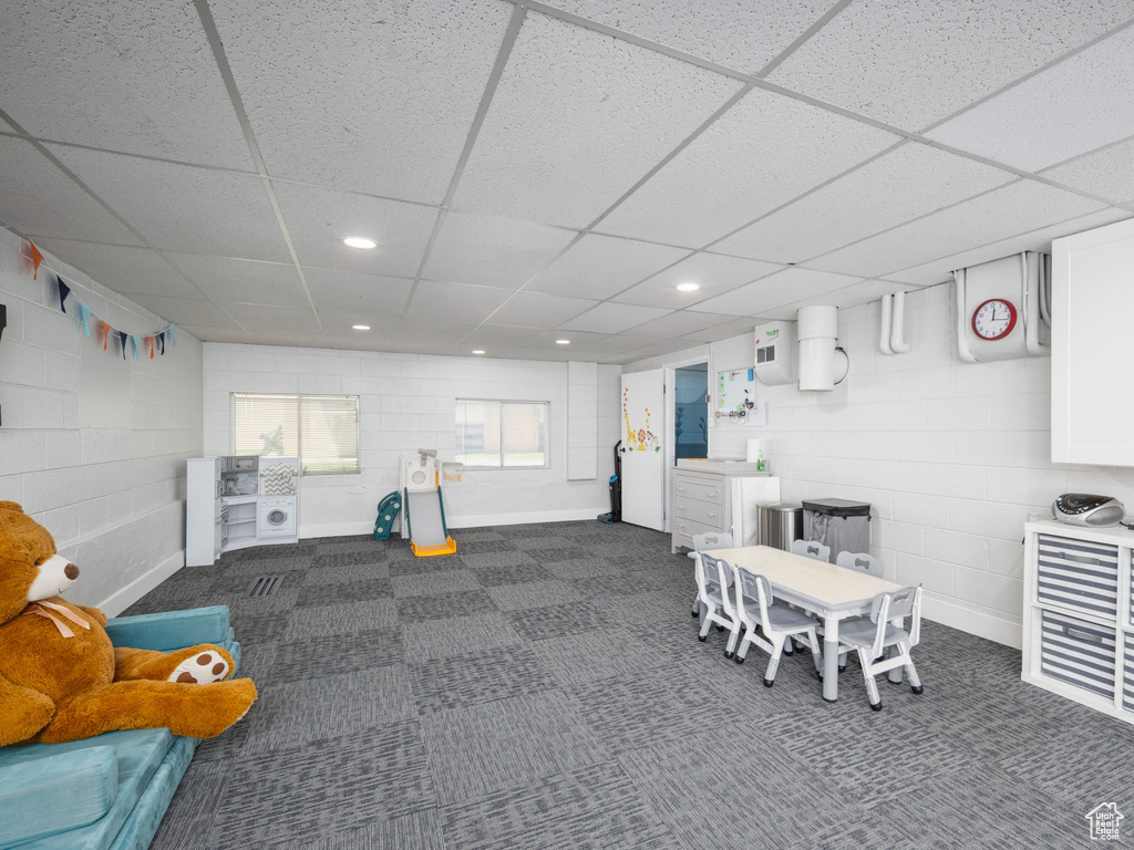Game room featuring a paneled ceiling, concrete block wall, recessed lighting, and dark carpet