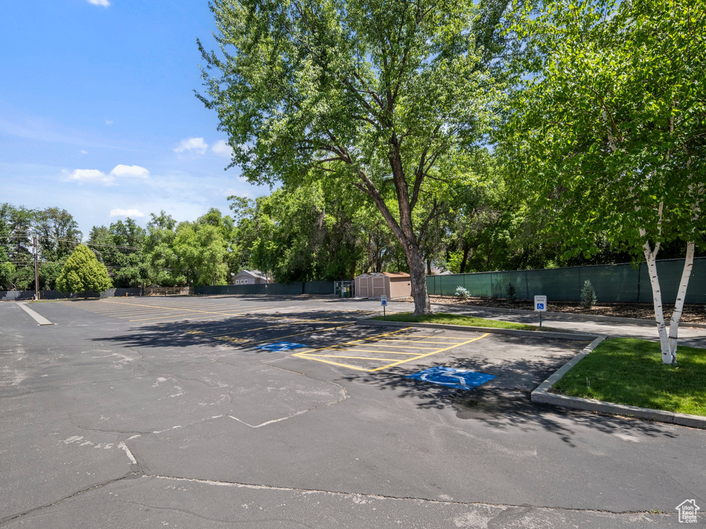 Uncovered parking lot featuring view of wooded area