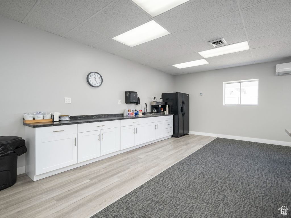 Misc room with a wall mounted air conditioner, a drop ceiling, and light wood-type flooring