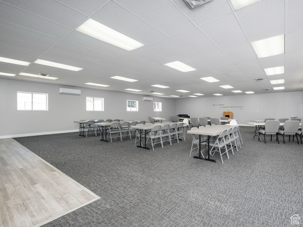 Carpeted dining area with a wall mounted AC and a drop ceiling