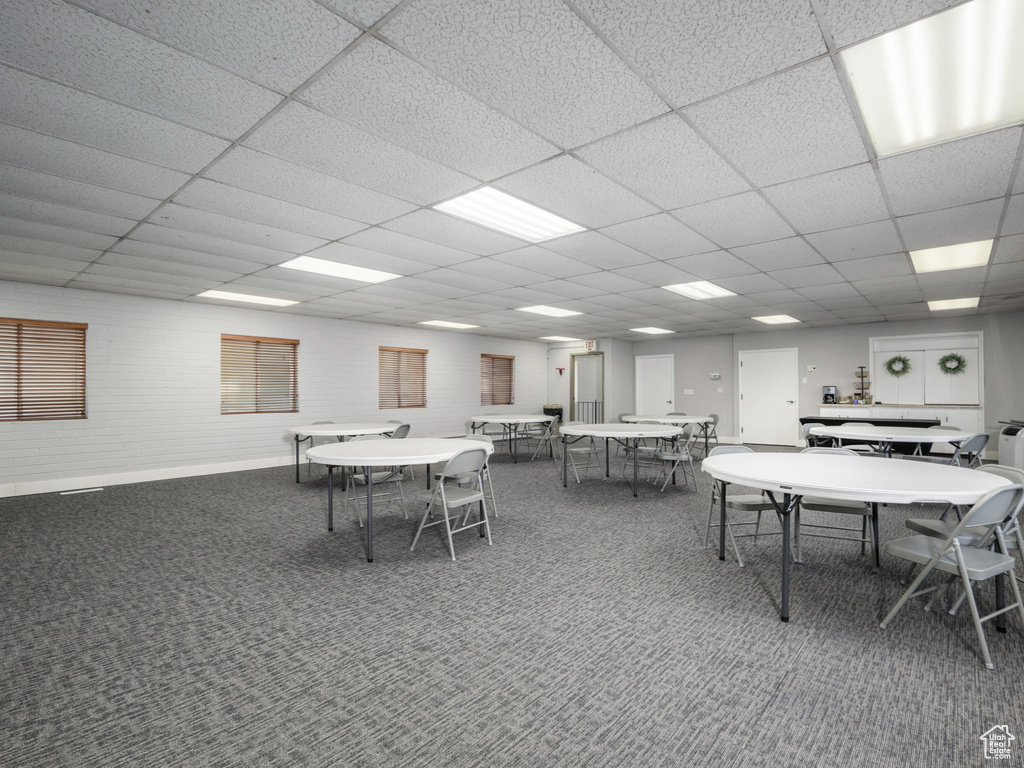 Carpeted dining room featuring a drop ceiling and baseboards