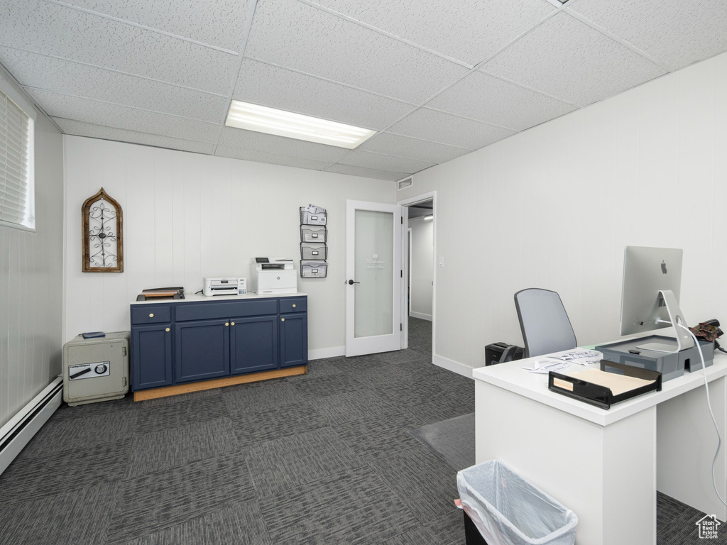 Home office featuring a baseboard heating unit, dark colored carpet, and a drop ceiling