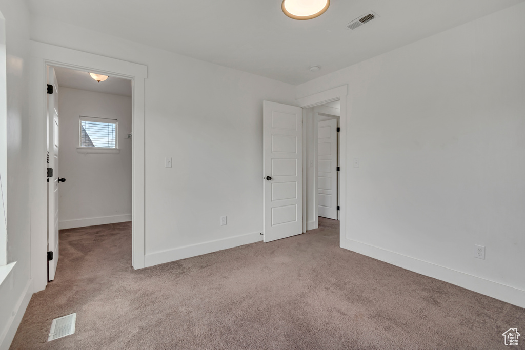 Unfurnished bedroom featuring carpet floors and a walk in closet