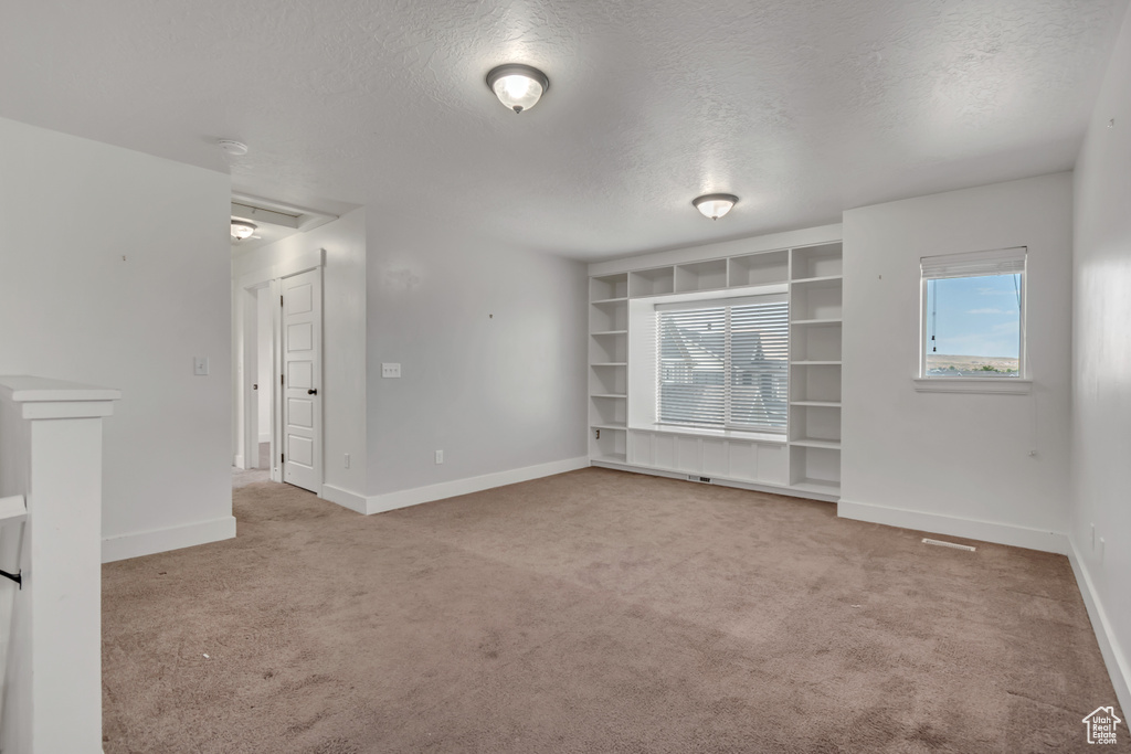 Empty room with a textured ceiling and light colored carpet