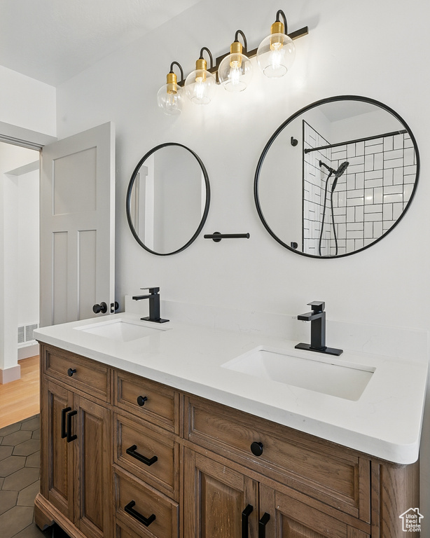 Bathroom with double vanity, tile patterned flooring, and a shower
