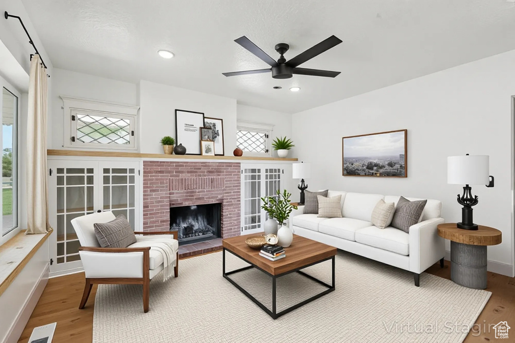 Living area with wood finished floors, a ceiling fan, a brick fireplace, and recessed lighting