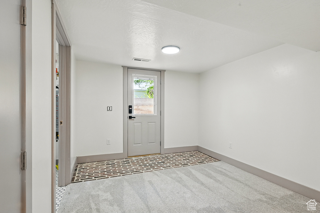 Carpeted foyer entrance featuring baseboards and a textured ceiling