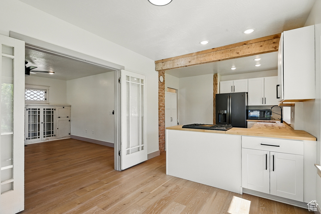 Kitchen featuring black appliances, light wood-style flooring, white cabinets, a peninsula, and recessed lighting